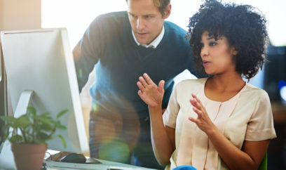 Shot of adults talking together at a workstation in an